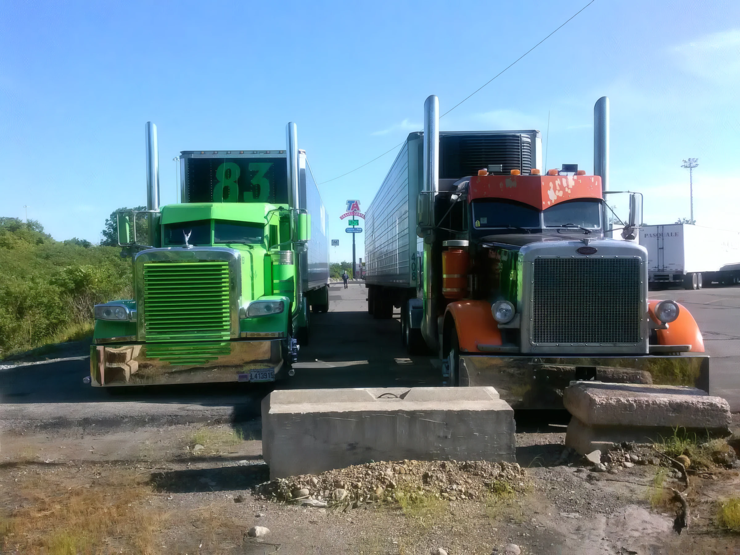 Two owner-operator Peterbilt tractors parked nose-out with dry van and reefer trailers at a truck stop